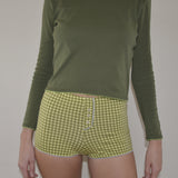 Person wearing a green long-sleeve shirt and green checkered shorts on a plain background