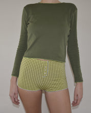 Person wearing a green long-sleeve shirt and green checkered shorts on a plain background